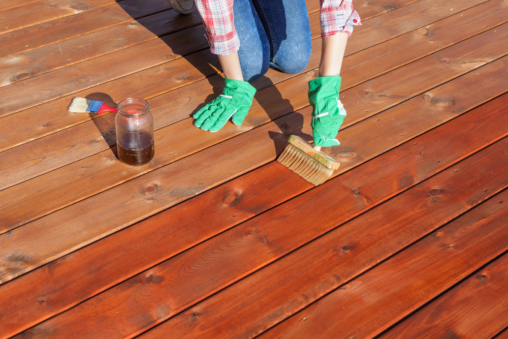 Woman Applying Protective Sealing On A Deck